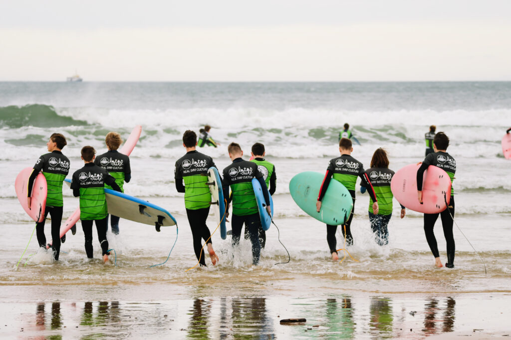 Gillingham School students running intro the sea with surfboards during a surf trip in Spain.